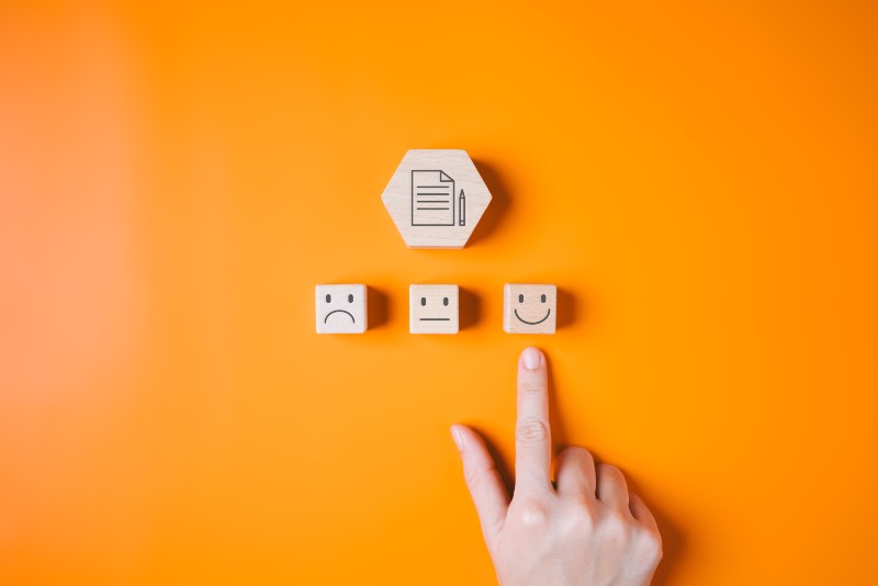 hand-choosing-happy-face-icon-on-wooden-blocks-2024-10-11-00-20-35-utc
