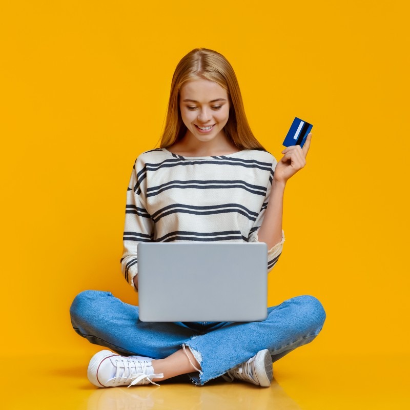 teen-girl-sitting-on-floor-with-laptop-and-credit-2023-11-27-04-53-26-utc